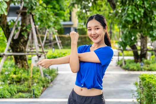 Strong athletic asian woman stretching warming up before running. Fit sport girl stretching her body warm up before workout outdoor. The girl in sportswear exercises outside for health and wellbeing photo