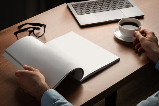 Man Reading Page of Magazine While Holding Coffee Cup photo