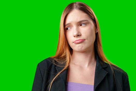 Young Woman Wearing Blazer Looks Skeptical Against Green Screen photo