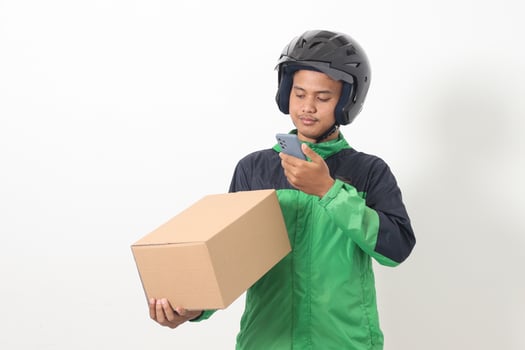Portrait of Asian online taxi driver wearing green jacket and helmet holding a box and scanning or capturing the package. Isolated image on white background photo