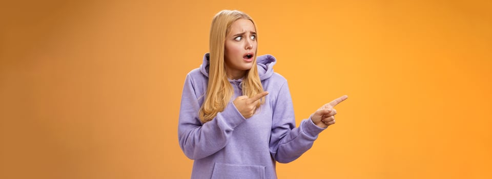 Concerned freak-out panicking funny blond girl gasping pop eyes drop jaw pointing left shocked stunned terrible scene friends boyfriend kissing anoyed standing upset and disappointed photo