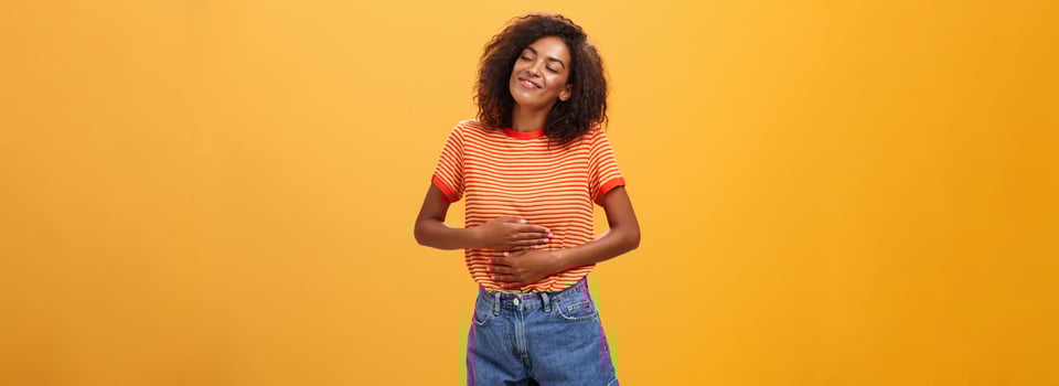 Mmm delicious meal warming me inside. Delighted stuffed good-looking stylish young female in striped t-shirt rubbing belly with satisfaction closing eyes from pleasure after eating tasty food photo