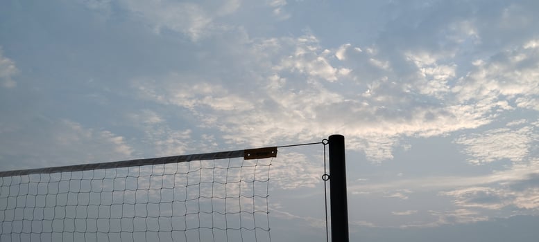 A volleyball net is shown against a cloudy sky photo