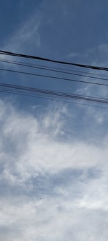 A plane flying over a city street with a power line photo