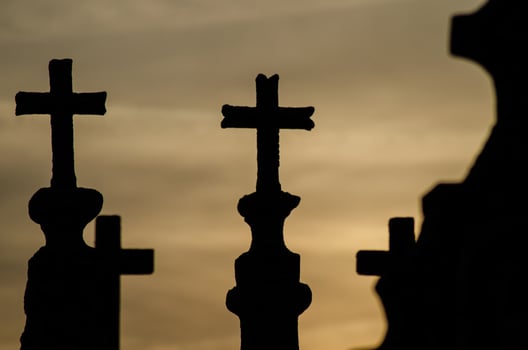 Silhouette of tomb crosses in a Christian cemetery at sunset. photo