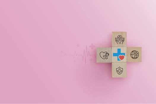 Hand arranging wood block with health care medical icon on pink background. health insurance, love, international cardiology day, check up, heart attack and cardiology. photo