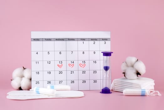 Women's menstrual pads, tampons, female menstruation calendar and alarm clock on a pink background. photo
