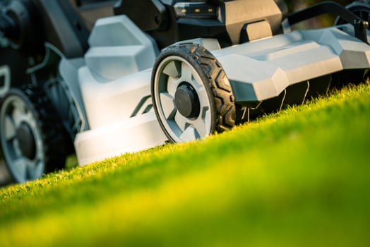 Mowing the Lush Green Lawn With a Modern Electric Lawn Mower in Bright Afternoon Sunlight photo
