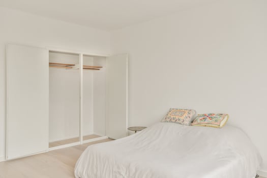 A white bedroom with a bed and a closet photo