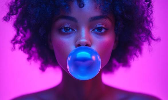 A woman with curly hair is blowing bubbles. The bubbles are blue and the woman is looking at the camera. The image has a fun and playful mood, as the woman is enjoying herself while blowing bubbles photo