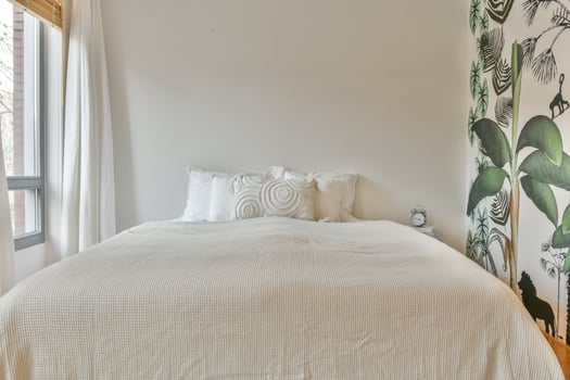 A bedroom with a white bed and a wall mural photo