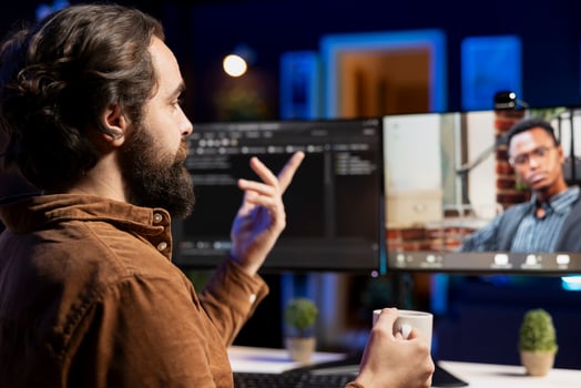 Engineer doing software debugging helped by BIPOC coworker in videocall meeting, checking errors in lines of code. IT worker fixing coding mistakes assisted by colleague in online teleconference photo