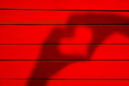 Two hands forming a heart shadow on red wood background photo