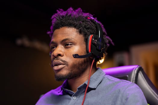 Close up shot of man in apartment playing videogames on gaming PC while chatting with teammates using headphones. Gamer contending against rival players, communicating with friends through headset photo