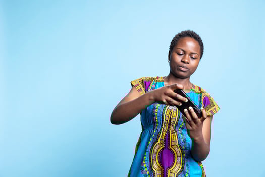 Cheerful woman playing online games on phone app, having fun with e sport tournament over blue background. Young adult enjoys gaming competition with mobile gameplay on camera. photo