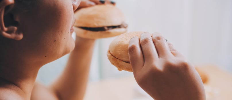 Binge eating disorder concept with woman eating fast food burger, fired chicken , donuts and desserts photo