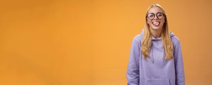 Funny charming female programmer having fun show tongue fool around coworkers during lunch break smiling broadly laughing in cute glasses purple hoodie, standing purple background photo