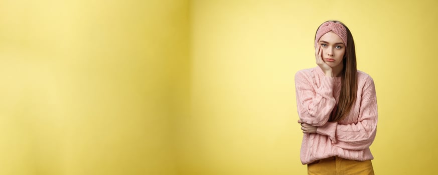 How boring. Indifferent upset gloomy girl missing party feeling bored leaning on palm reluctant, sad looking careless at camera visiting uninteresting lecture, suffering boredom over yellow wall photo
