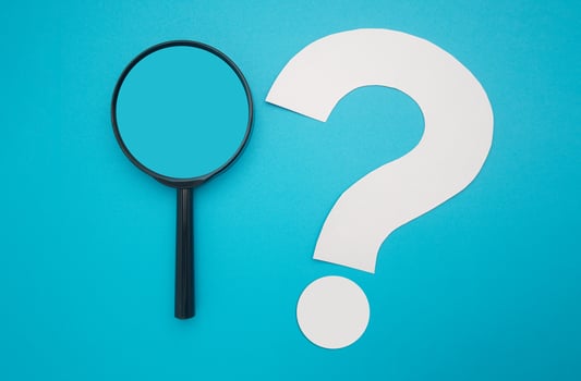 Search and question mark concept. A magnifying glass and a white question mark symbol are on a blue background. Top view. Space for text photo