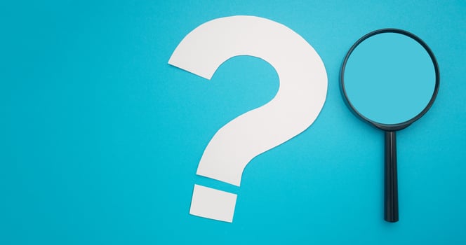 A magnifying glass and a white question mark symbol are on a blue background. Search and question mark concept. Top view. Space for text photo