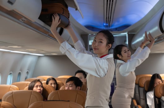 Airplane flight attendant putting luggage and closing overhead luggage cabin in airplane photo