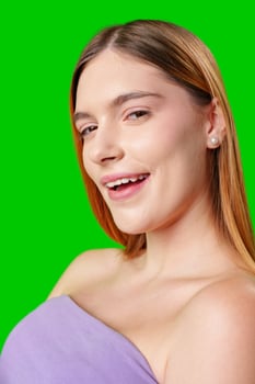 Young Woman With Long Brown Hair Smiles in a Purple Top Against Green Screen photo