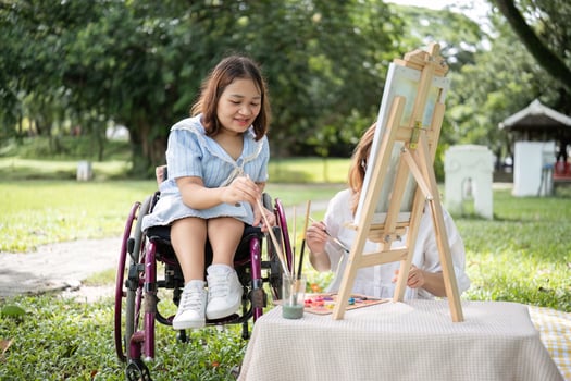 Young Disabled Woman and Friend Enjoy Painting Together in a Garden on a Sunny Day photo