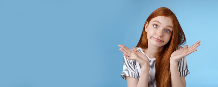 Unsure clueless cute silly redhead female part-time worker shrugging careless raise hands unaware smirking tilting head lift eyebrows confused cannot answer no idea standing blue background photo