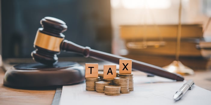 Tax law concept. Wooden blocks word TAX on coin stack .with gavel and money on the table. photo