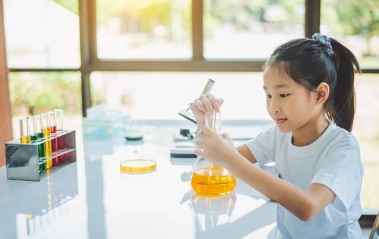 little scientist looking through a microscope and test tubes filled with chemicals for learning about science and experiments. photo