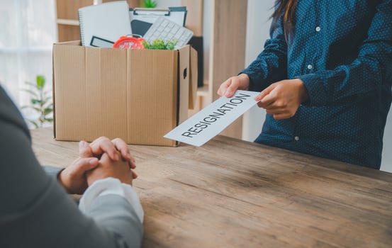 female company employee hands a white envelope with a resignation letter inside to her boss or HR before leaving her workplace. photo