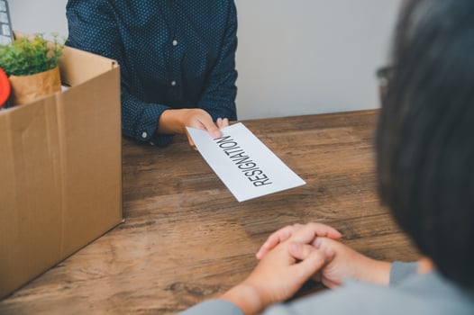 female company employee hands a white envelope with a resignation letter inside to her boss or HR before leaving her workplace. photo