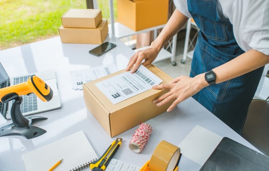 startup young female small business owners attaching shipping labels to cardboard boxes or parcels for delivery of customer orders-concept shopping online photo