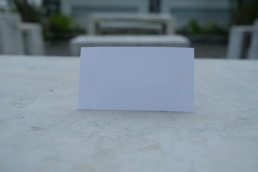Blank white card on a concrete surface with a blurred background. photo