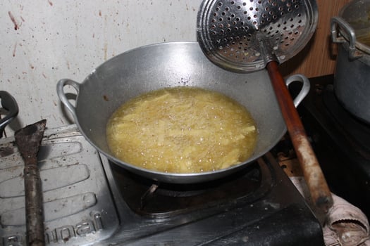 Deep frying food in a large metal pan on a stovetop. photo