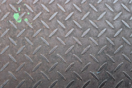 Rusty metal diamond plate texture with green paint splatter. photo