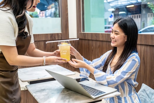 Waiter serving glass of fresh juice to a customer who was a young asian woman on table in the restaurant, Juice bar employees serving drink to customer, good service, Good-natured atmosphere photo