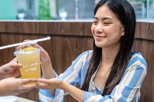 Waiter serving glass of fresh juice to a customer who was a young asian woman on table in the restaurant, Juice bar employees serving drink to customer, good service, Good-natured atmosphere photo