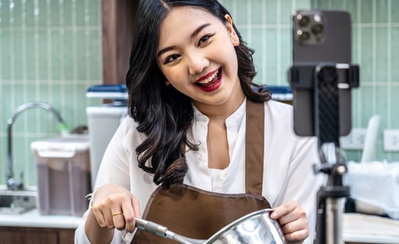 Young asian women is shop owner Put on an apron making cream for cupcakes, Using electric mixer, Preparing Cookies, Cooking, Homemade, Made specifically to sell, and recording for food blog photo