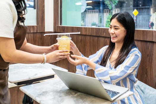 Waiter serving glass of fresh juice to a customer who was a young asian woman on table in the restaurant, Juice bar employees serving drink to customer, good service, Good-natured atmosphere photo
