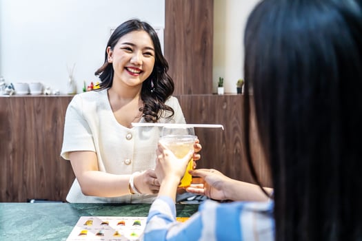 Waiter serving glass of fresh juice to a customer who was a young asian woman on counter in the restaurant, Juice bar employees serving drink to customer, good service, Good-natured atmosphere photo