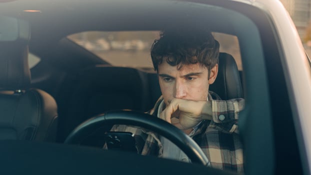Displeased upset sad Caucasian man guy male driver car owner inside automobile on parking lot using mobile phone problem with smartphone read bad news frustrated anxious millennial driving auto city photo