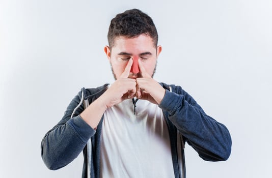 Suffering man with nasal congestion isolated. Sore person suffering with nasal bridge on isolated background photo