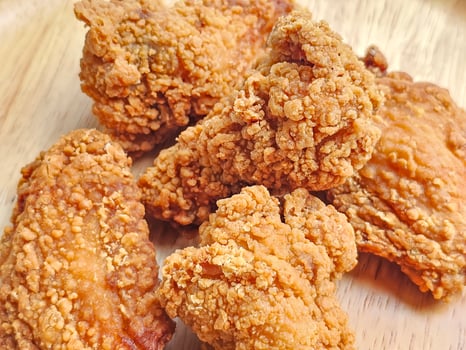 Close up, group of fried chicken wings arranged on wooden plate photo