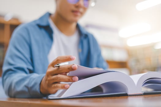 Close-up of student hand reading book in library to study.back to school concept photo