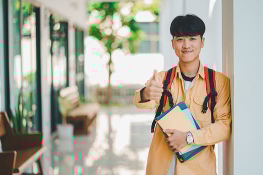 Happy smiling student with book in hand on campus while going to study for learning. photo