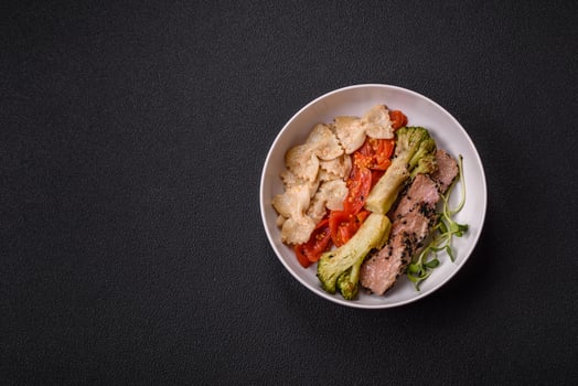 Bowl with slices of baked tuna with broccoli, tomatoes and fusili pasta photo