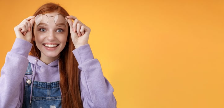 Impressed excited happy pleased young silly lovely redhead girl receive pleasing surprise take off glasses wide eyes touched smiling delighted gasping amazed feel upbeat thrilled photo