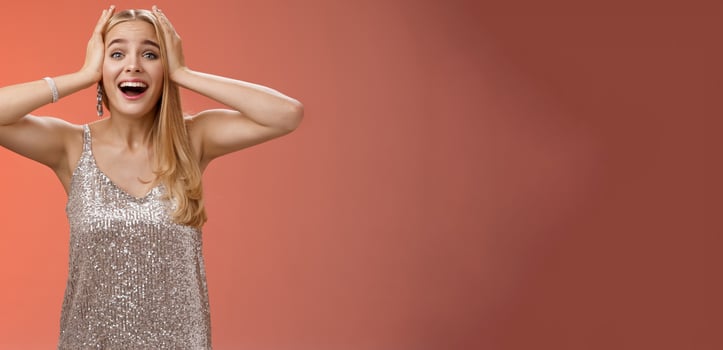 Amazed excited nervous young beautiful blond woman in silver stylish dress cannot believe own luck happiness hold hands head smiling screaming astonished positive awesome news, triumphing photo