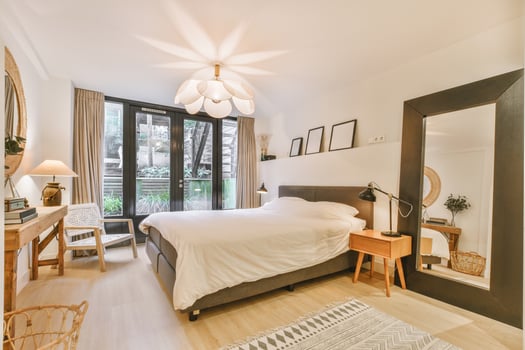 A bedroom with a bed, a mirror and a window photo